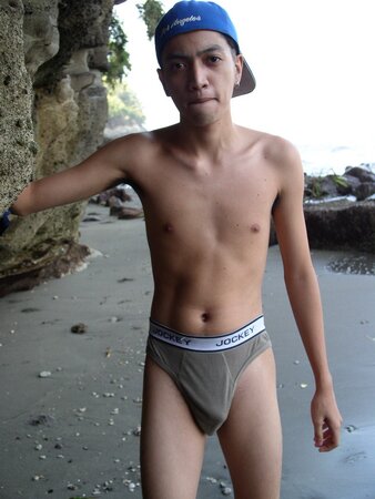Young twink Adrial gets completely naked on the beach and strokes his cock