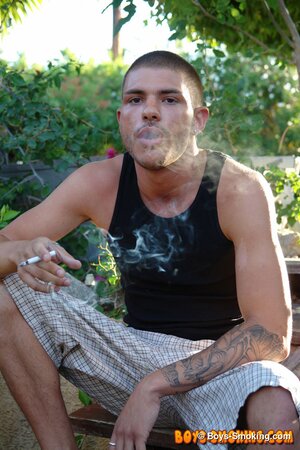 Tattooed chainsmoker Tristan Matthews lights up and strokes outside in the sun