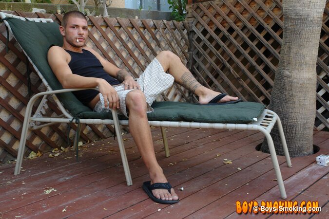 Tattooed chainsmoker Tristan Matthews lights up and strokes outside in the sun