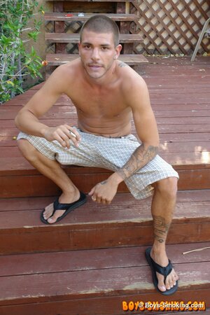Tattooed chainsmoker Tristan Matthews lights up and strokes outside in the sun