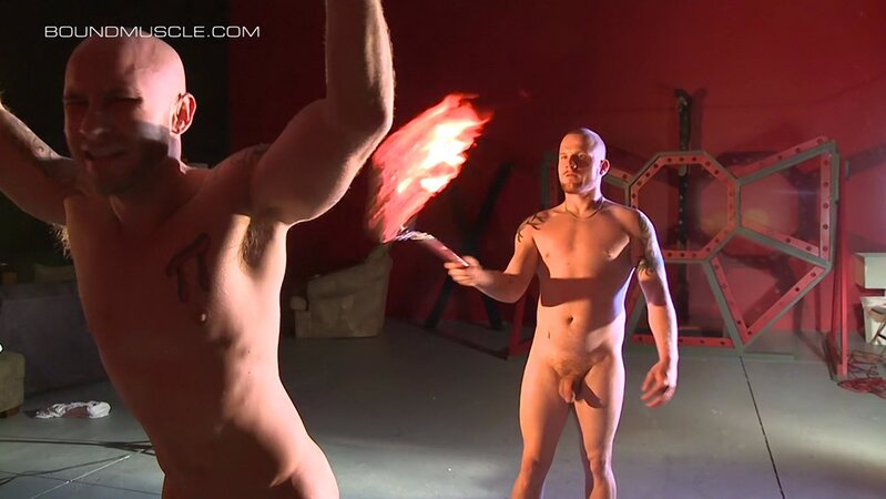 Luke Riley brings a flaming flogger dangerously close to the skin of Drake Jaden