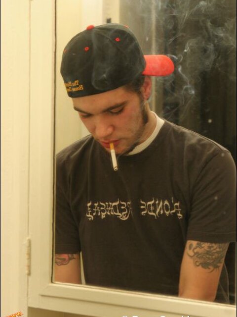 Zack smokes a cigarette while shaving in bathroom