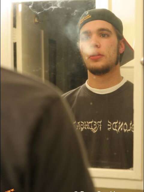 Zack smokes a cigarette while shaving in bathroom