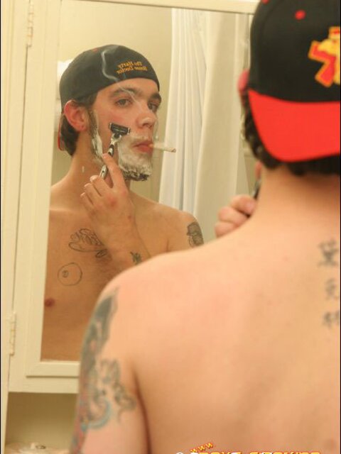 Zack smokes a cigarette while shaving in bathroom