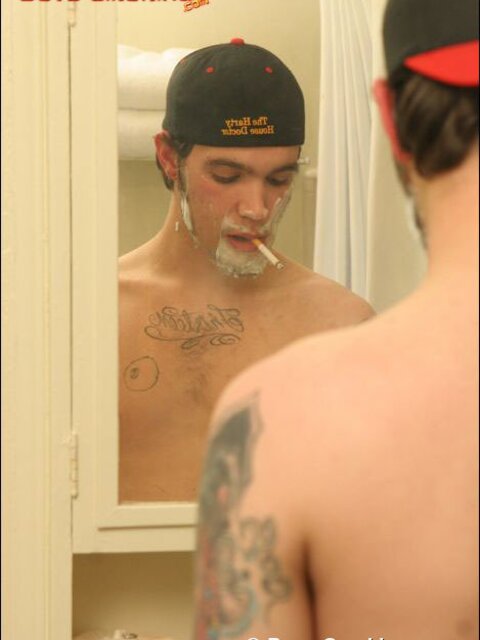 Zack smokes a cigarette while shaving in bathroom