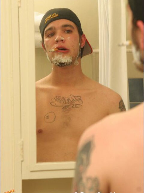 Zack smokes a cigarette while shaving in bathroom