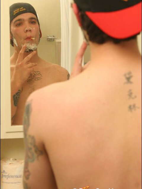 Zack smokes a cigarette while shaving in bathroom