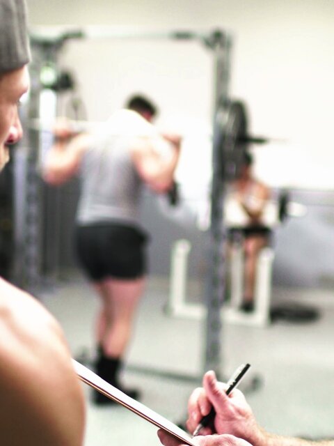 Personal trainer Nick Fitt gets real close to client Roman Todd at the gym